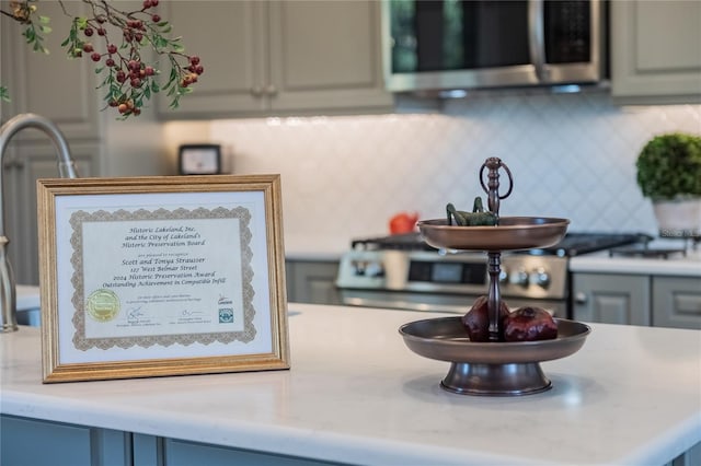 details featuring tasteful backsplash, gray cabinets, and range