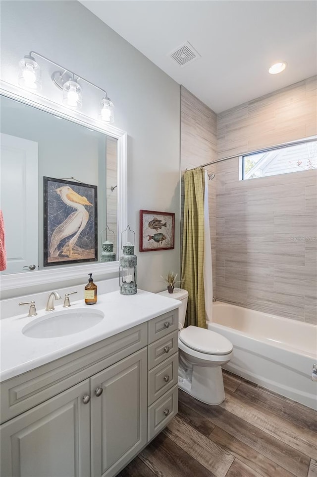 full bathroom featuring wood-type flooring, toilet, shower / tub combo, and vanity