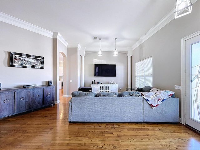 living room with decorative columns, ornamental molding, and dark wood-type flooring