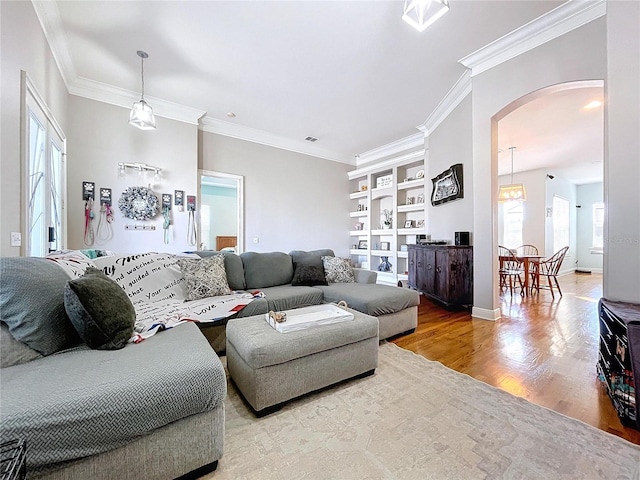 living room featuring crown molding, wood-type flooring, and built in features