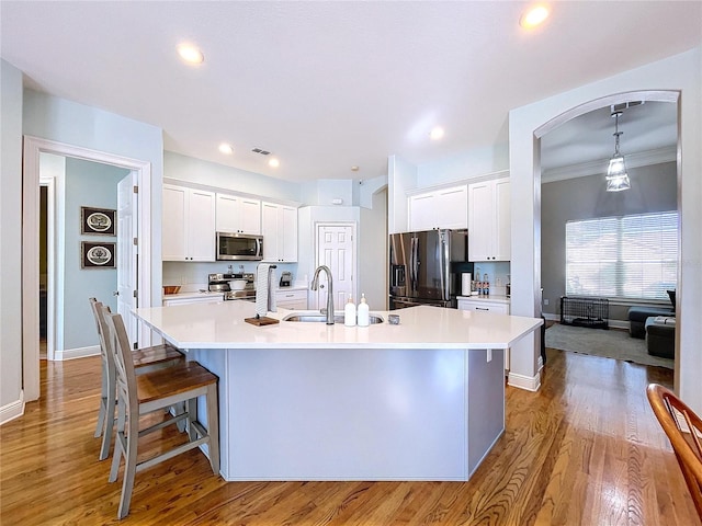 kitchen with stainless steel appliances, a large island, hanging light fixtures, and white cabinets