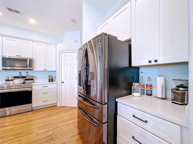 kitchen featuring appliances with stainless steel finishes, light hardwood / wood-style flooring, and white cabinets