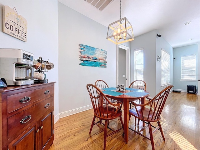 dining room with an inviting chandelier, a wealth of natural light, and light hardwood / wood-style floors