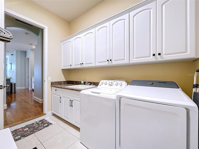 laundry area with cabinets, light tile patterned flooring, sink, and independent washer and dryer