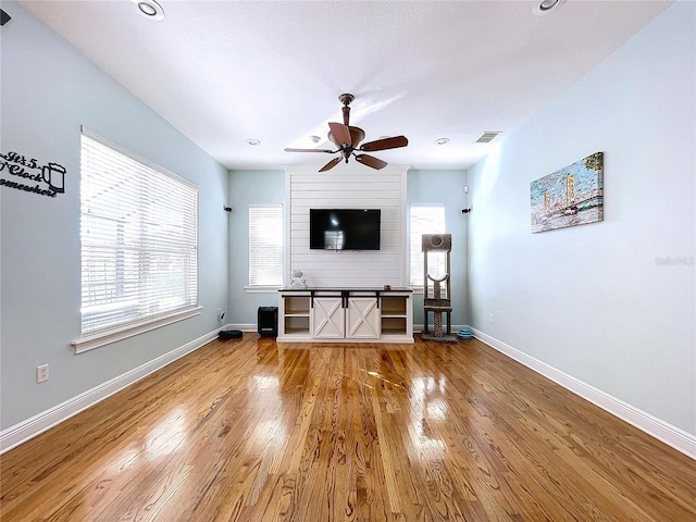 unfurnished living room with a healthy amount of sunlight, hardwood / wood-style floors, and ceiling fan