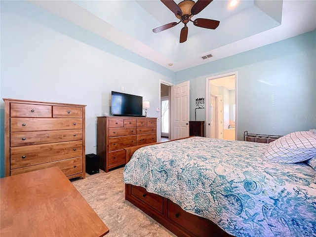 bedroom with light carpet, a tray ceiling, and ceiling fan