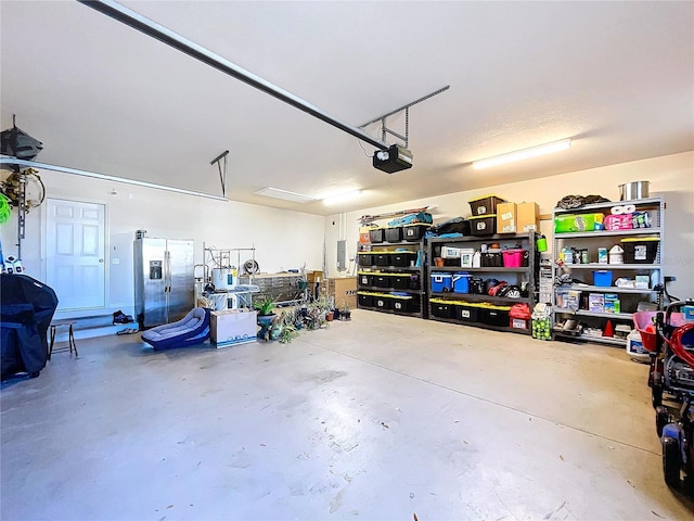 garage with stainless steel fridge with ice dispenser and a garage door opener