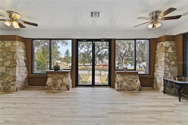 unfurnished sunroom with wood ceiling, ceiling fan, and a healthy amount of sunlight