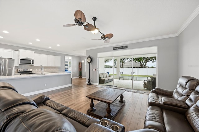 living room featuring ornamental molding, light hardwood / wood-style floors, and ceiling fan