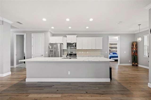 kitchen with a spacious island, sink, light stone counters, appliances with stainless steel finishes, and white cabinets