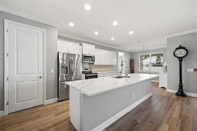 kitchen with appliances with stainless steel finishes, white cabinetry, sink, a kitchen island with sink, and light stone countertops