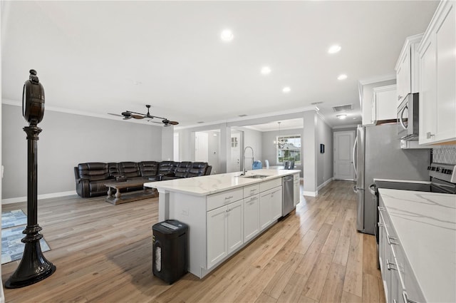 kitchen featuring sink, crown molding, white cabinetry, stainless steel appliances, and a center island with sink