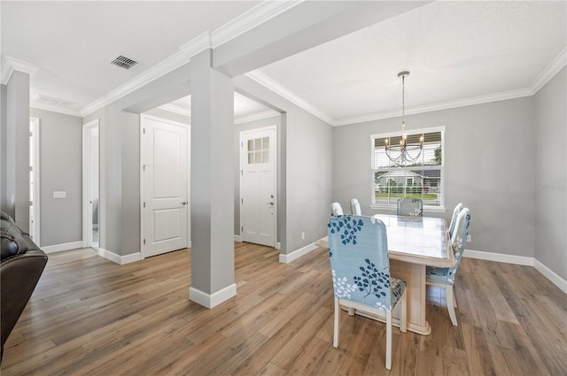 dining area featuring hardwood / wood-style floors, ornamental molding, and a chandelier