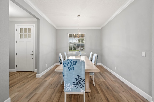 dining area with ornamental molding, hardwood / wood-style floors, a notable chandelier, and a textured ceiling