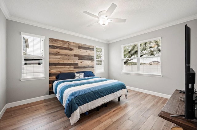 bedroom with crown molding, light wood-type flooring, a textured ceiling, and ceiling fan