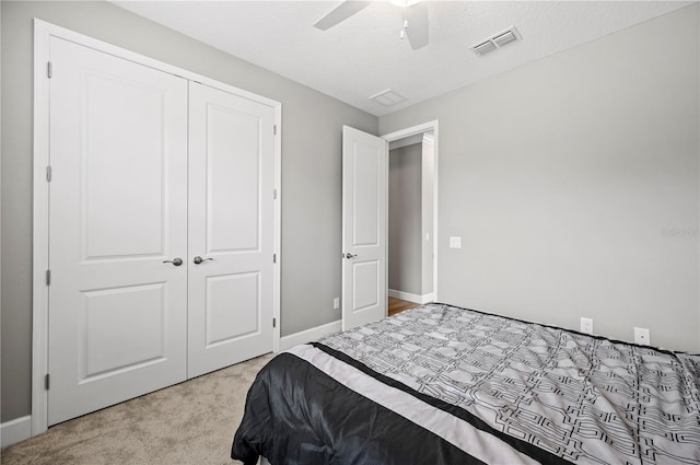 carpeted bedroom with a textured ceiling, ceiling fan, and a closet