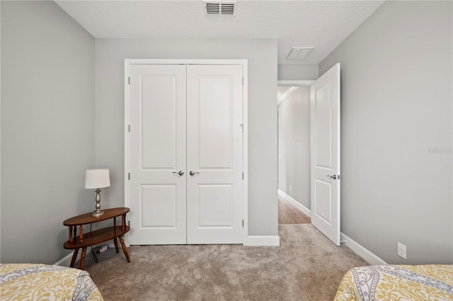 bedroom with light colored carpet, a textured ceiling, and a closet