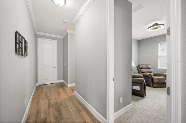 hallway featuring ornamental molding, a textured ceiling, and light wood-type flooring