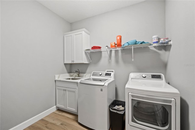 clothes washing area with light hardwood / wood-style floors, sink, cabinets, and independent washer and dryer