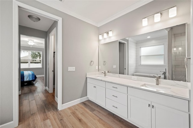 bathroom featuring crown molding, vanity, hardwood / wood-style floors, and a washtub