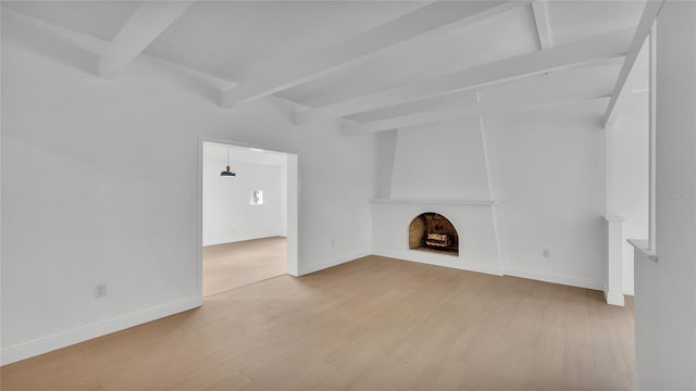 unfurnished living room featuring beam ceiling and light hardwood / wood-style floors