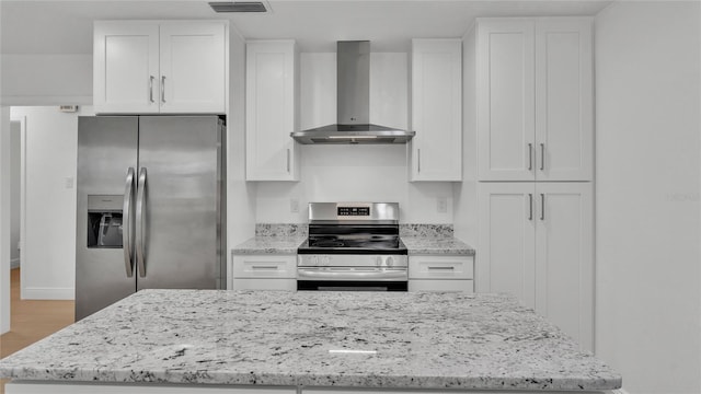 kitchen featuring hardwood / wood-style floors, white cabinetry, stainless steel appliances, light stone countertops, and wall chimney exhaust hood