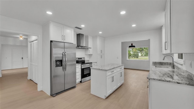 kitchen featuring wall chimney range hood, sink, white cabinetry, stainless steel appliances, and light stone countertops