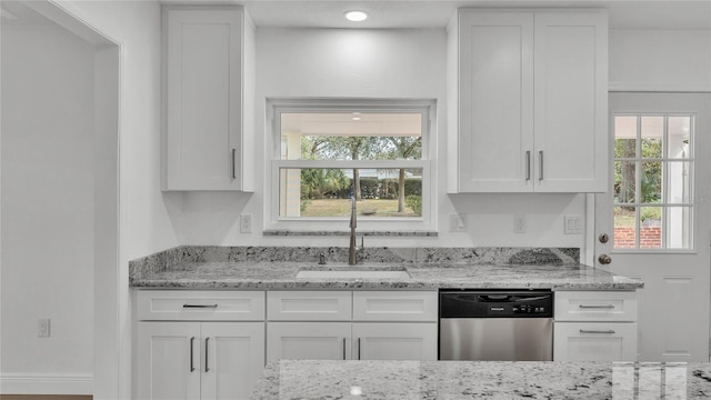 kitchen with light stone counters, sink, stainless steel dishwasher, and white cabinets