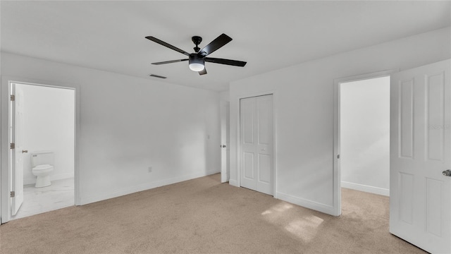 unfurnished bedroom featuring ceiling fan, ensuite bath, and light colored carpet