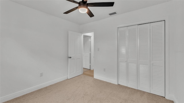 unfurnished bedroom with ceiling fan, light carpet, and a closet