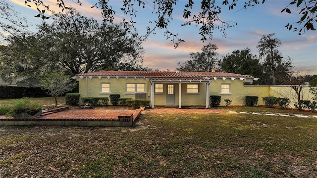 back house at dusk with a lawn