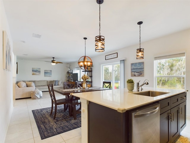 kitchen with decorative light fixtures, sink, stainless steel dishwasher, dark brown cabinetry, and a center island with sink