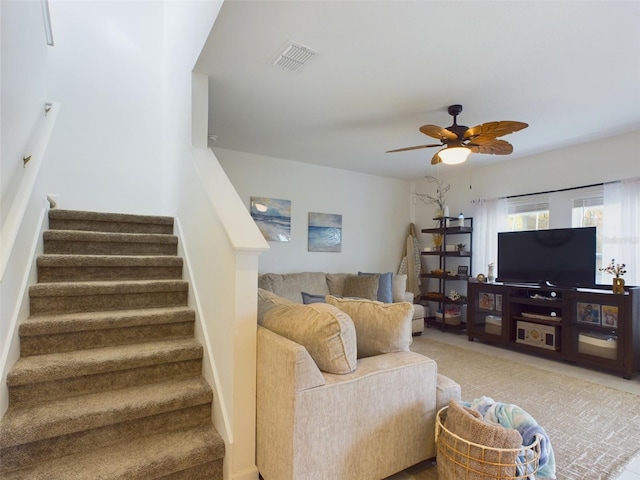 living area featuring visible vents, ceiling fan, and stairs