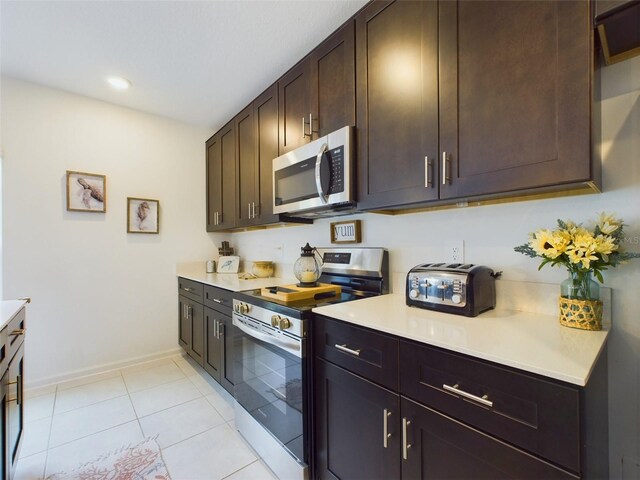 kitchen featuring stainless steel appliances, light countertops, dark brown cabinets, and light tile patterned flooring