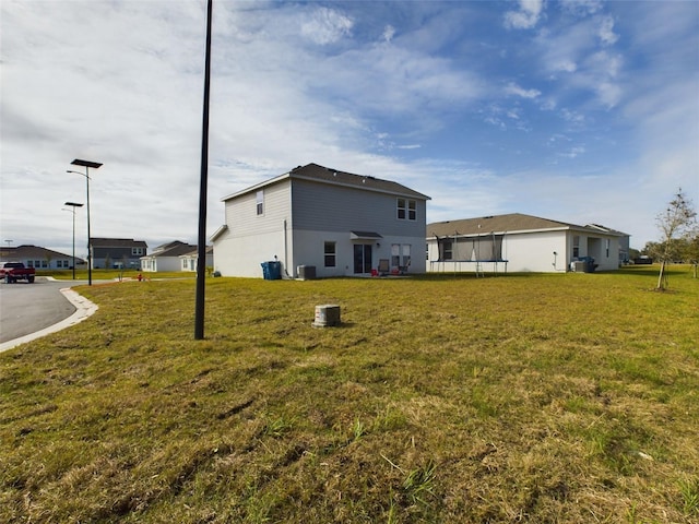 rear view of house featuring a yard and central air condition unit