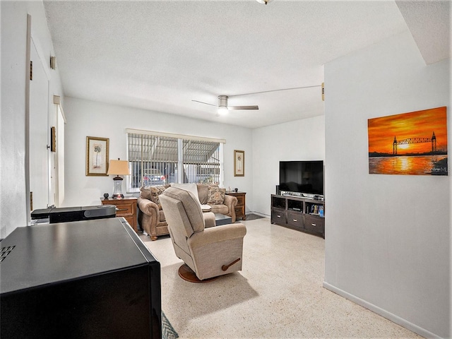 living room featuring ceiling fan and a textured ceiling