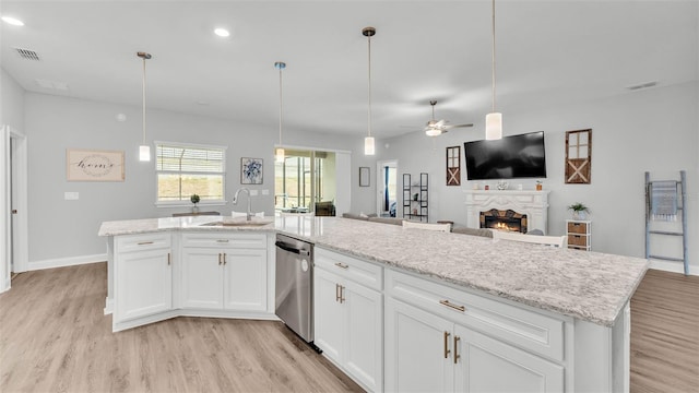 kitchen with a kitchen island with sink, sink, stainless steel dishwasher, and white cabinets