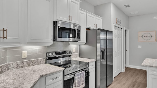 kitchen featuring backsplash, appliances with stainless steel finishes, light hardwood / wood-style flooring, and white cabinets