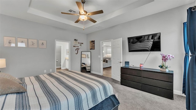 bedroom featuring a raised ceiling, ceiling fan, and carpet flooring