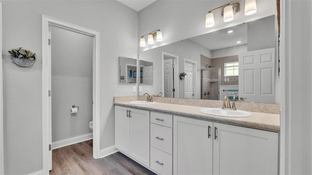 bathroom with wood-type flooring, toilet, an enclosed shower, and vanity