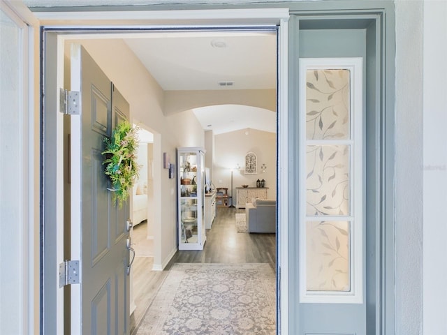 hall with vaulted ceiling and light hardwood / wood-style floors