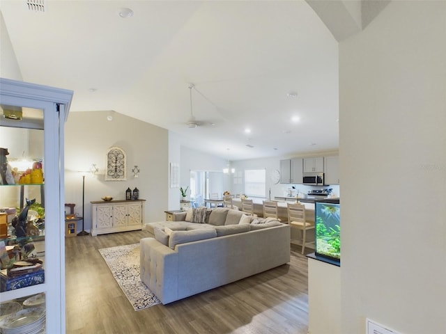 living room featuring lofted ceiling, a notable chandelier, and light wood-type flooring