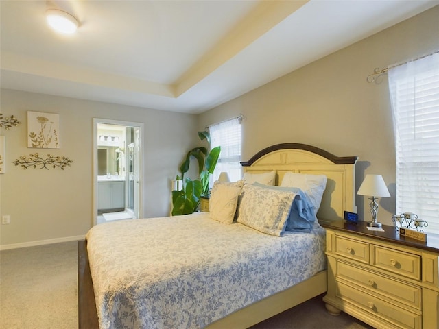 carpeted bedroom with a raised ceiling and ensuite bathroom