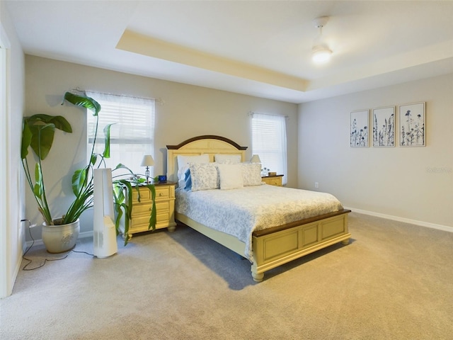 bedroom featuring light colored carpet and a tray ceiling