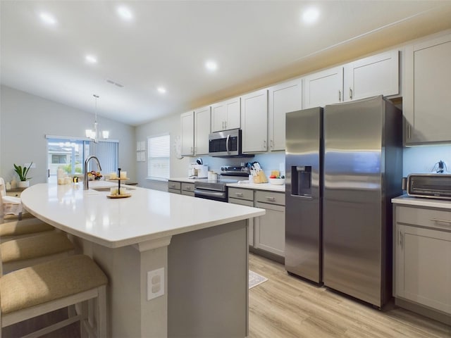 kitchen featuring stainless steel appliances, pendant lighting, sink, and a center island with sink