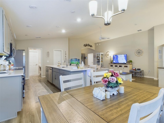 dining area featuring sink, vaulted ceiling, a chandelier, and light wood-type flooring