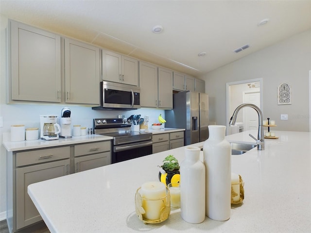 kitchen featuring lofted ceiling, stainless steel appliances, sink, and gray cabinetry