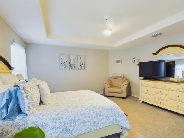 bedroom with a tray ceiling and light colored carpet