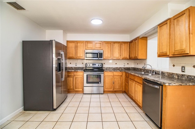 kitchen featuring tasteful backsplash, sink, stainless steel appliances, and light tile patterned flooring