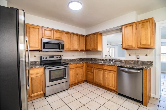 kitchen featuring light tile patterned flooring, appliances with stainless steel finishes, sink, backsplash, and dark stone counters